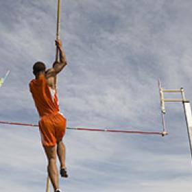 一名男子运动员在天空中撑杆跳的低角度镜头